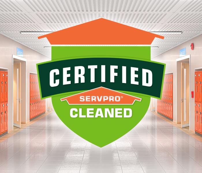 Certified: SERVPRO Cleaned logo on a backdrop of lockers lining a long hallway.