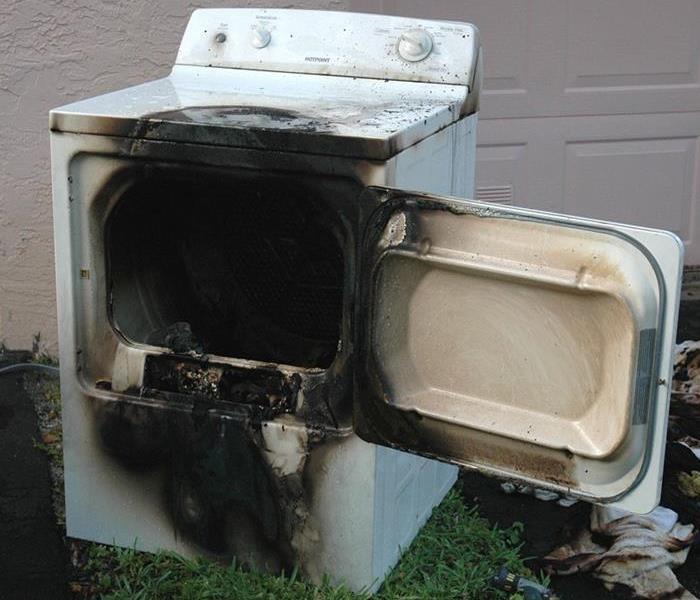 A charred and unusable dryer, damaged by a fire.