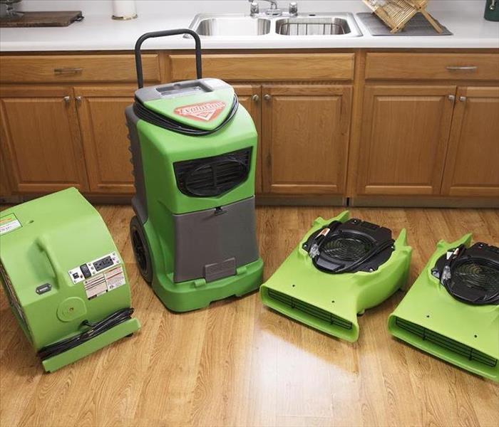 SERVPRO equipment lined up on a vinyl faux wood floor.