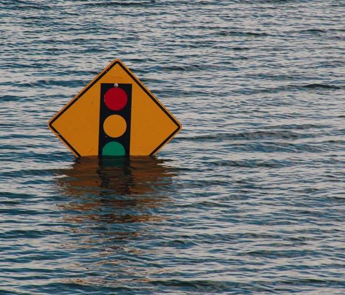 A "traffic light ahead" sign submerged in water from floods.